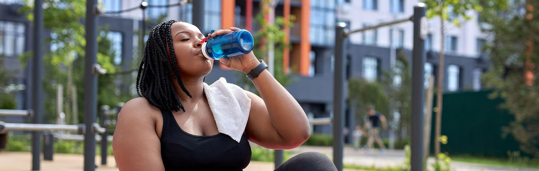A healthy woman drinking water after working out