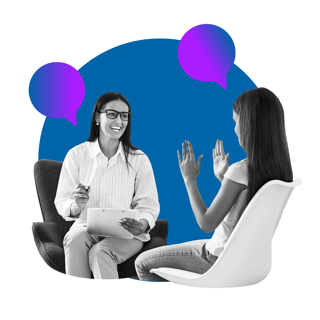 Two people seated in conversation, one smiling while holding a tablet and pen as the other gestures with both hands