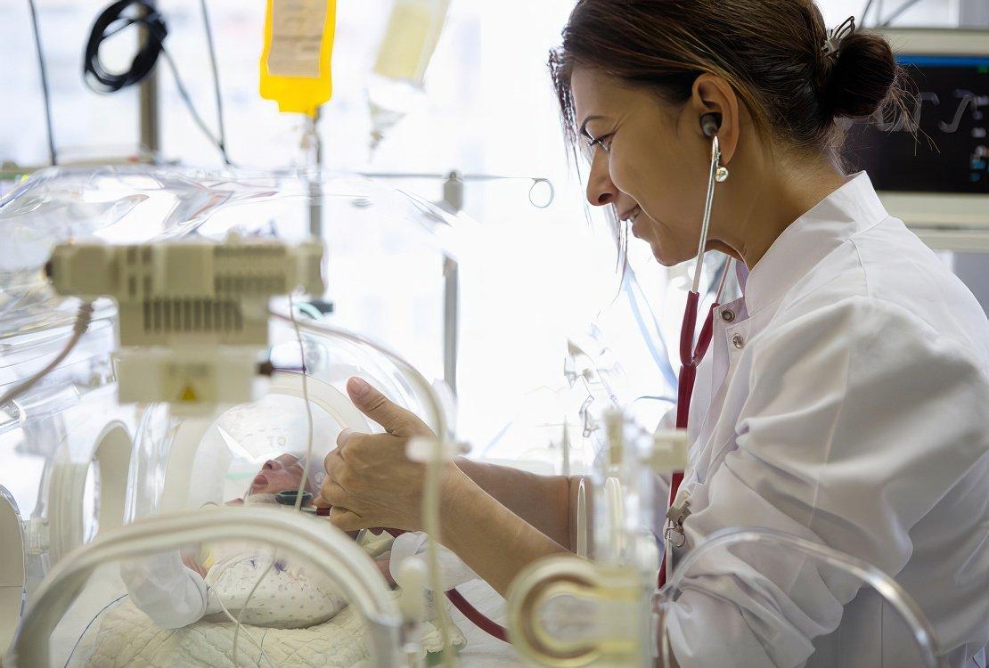 Infant in incubator with doctor