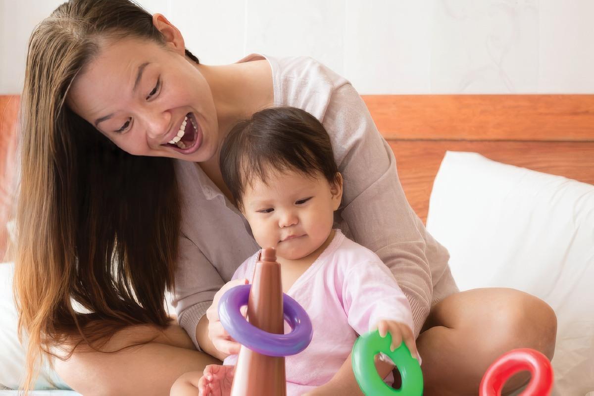 Mom and baby playing with toys on the bed