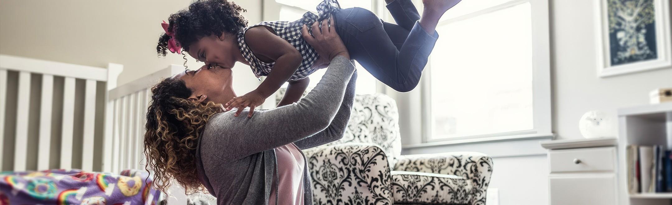 A mother spending time with her daughter picking her up over her head and giving her a kiss