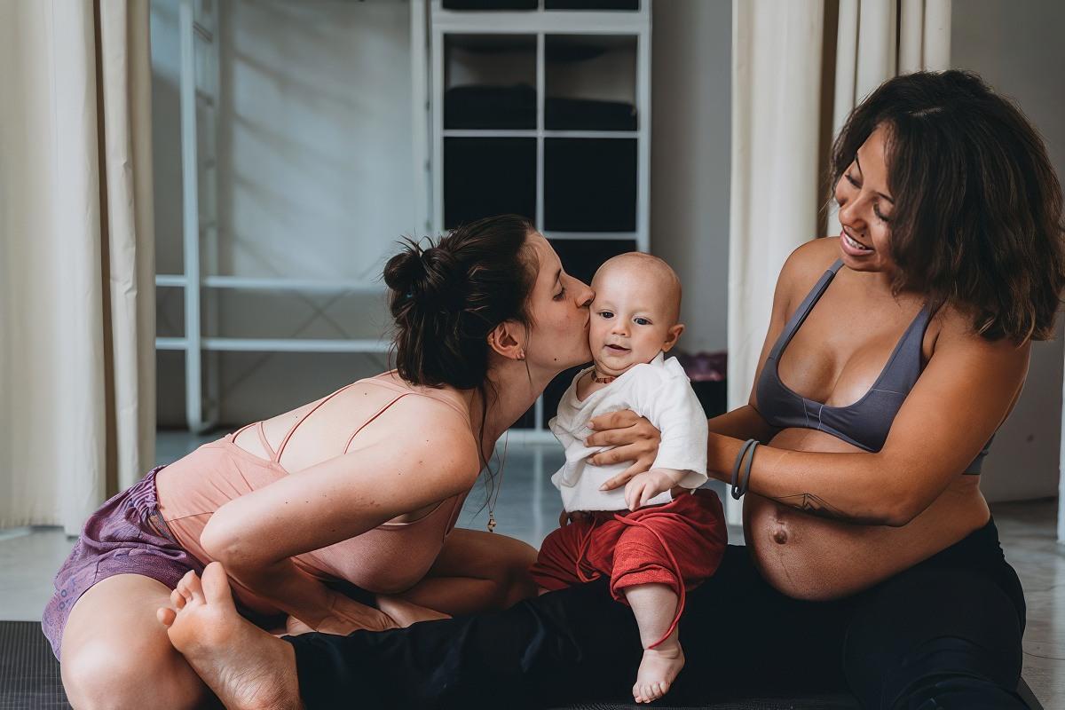 A healthy pregnant woman holding a healthy baby while his mom kisses him.