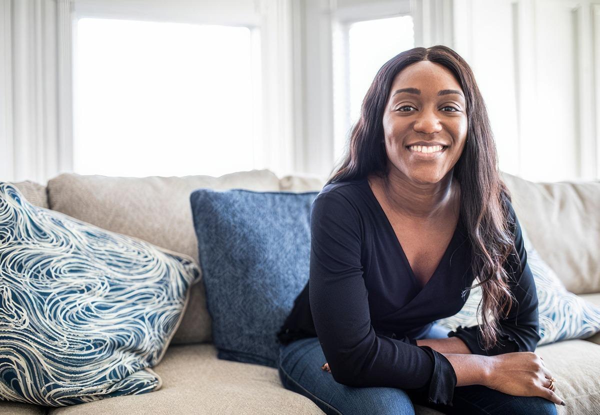 An expectant mom sitting on her couch smiling after her Home Visit.