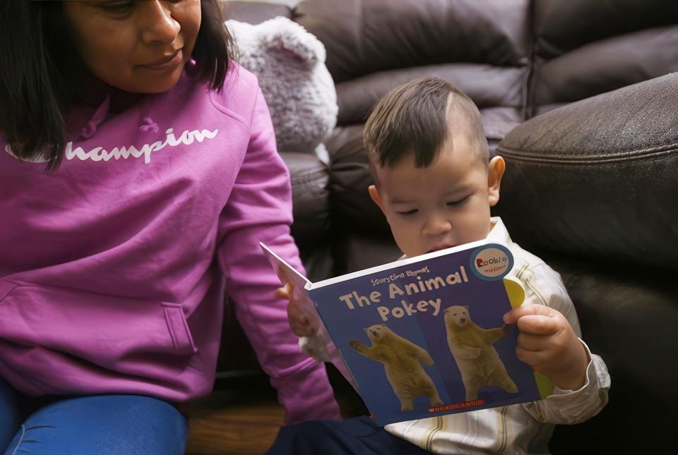 A child age 0-3 and his mom reading a book as an educational activity.